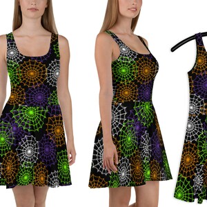 Puede incluir: Un vestido skater negro con un patrón de telaraña en naranja, verde, blanco y morado. El vestido tiene un escote redondo y es sin mangas.