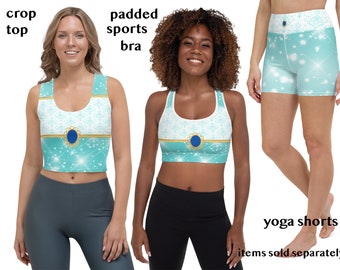 May include: A crop top, padded sports bra, and yoga shorts set. The activewear features a light blue and white design with a gold trim and a blue jewel accent. The set is designed with a snowflake pattern and sparkling accents.