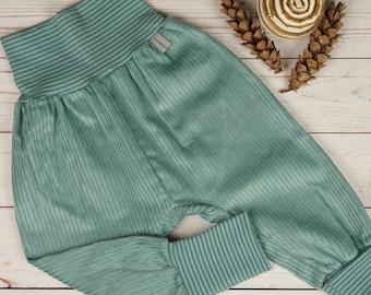 May include: Teal ribbed corduroy pants with a wide elastic waistband. The pants have a relaxed fit and cuffed legs.