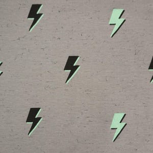May include: A grey fabric background with a repeating pattern of black and light green lightning bolts.
