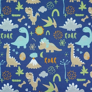 Pode incluir: Tecido azul com um padrão repetido de dinossauros, incluindo um tricerátopo, um estegossauro e um pterodáctilo. O tecido também apresenta a palavra "ROAR" em laranja.