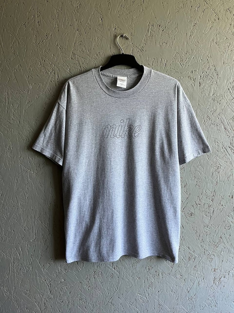 May include: A grey t-shirt with a black outlined "nike" logo.