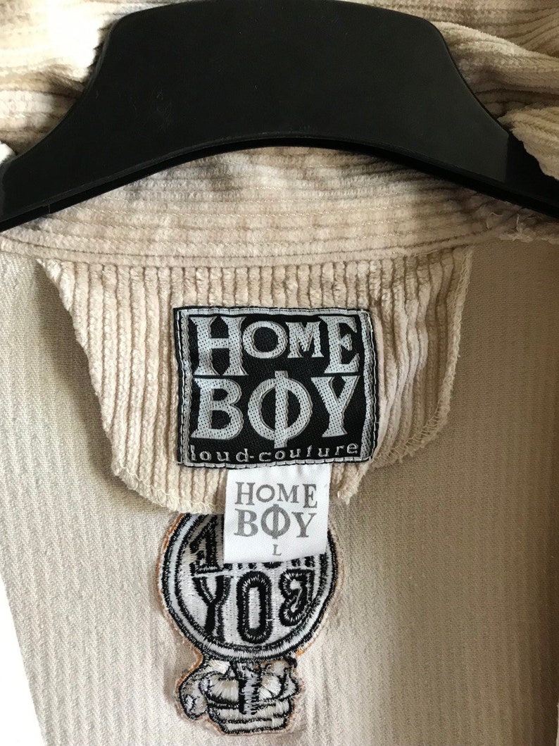 May include: A beige corduroy jacket with a black "HOME BOY loud-couture" label and a black and white embroidered patch that says "HOME BOY" in a circle.