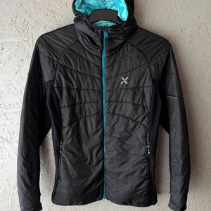 May include: Black hooded jacket with a turquoise interior and zip. The jacket has a quilted design on the front and a small logo on the chest. The jacket is hanging on a black hanger.