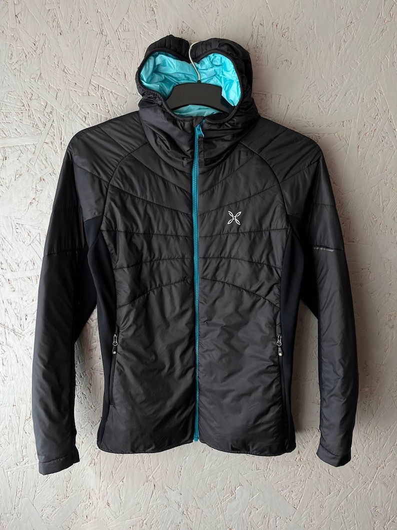 May include: Black hooded jacket with a turquoise interior and zip. The jacket has a quilted design on the front and a small logo on the chest. The jacket is hanging on a black hanger.