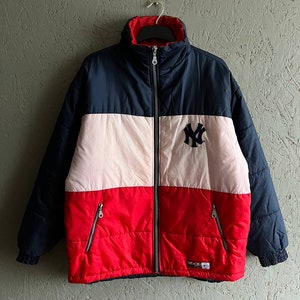 Könnte beinhalten: Eine blaue, weiße und rote, farbig unterteilte Steppjacke mit Reißverschluss und einem New York Yankees Logo auf der Vorderseite.