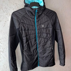 May include: Black hooded jacket with a light blue interior and a turquoise zip. The jacket has a quilted design on the front and a small white logo on the chest. The sleeves are black and the jacket is hanging on a black hanger.