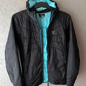 May include: Black hooded jacket with a turquoise interior and zip. The jacket has a quilted design and a small white logo on the chest. The hood and zip are outlined in turquoise. The jacket is hanging on a black hanger.
