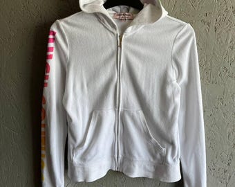 May include: White hooded zip-up sweatshirt with rainbow colored stripes on the sleeves and a Juicy Couture logo on the front.