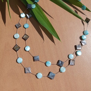 Op de afbeelding: Een dubbele ketting met ronde en vierkante turquoise en zwarte schelp kralen.