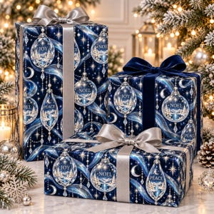 May include: Three rectangular gift boxes wrapped in dark blue paper featuring a pattern of crystal ornaments with the words JOY, NOEL, and PEACE. The boxes are tied with silver and navy blue ribbons, accented with sparkling stars and swirls.