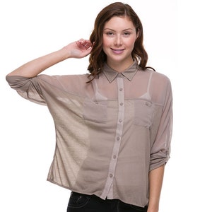 May include: A light brown, semi-sheer button-down shirt with long sleeves and two chest pockets. The shirt has a relaxed fit and is made of a lightweight fabric.