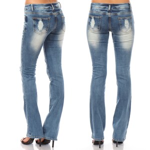 May include: Light blue denim jeans with distressed details on the front and back pockets. The jeans have a slight flare at the bottom and are worn with black high-heeled sandals. The jeans are a classic style.