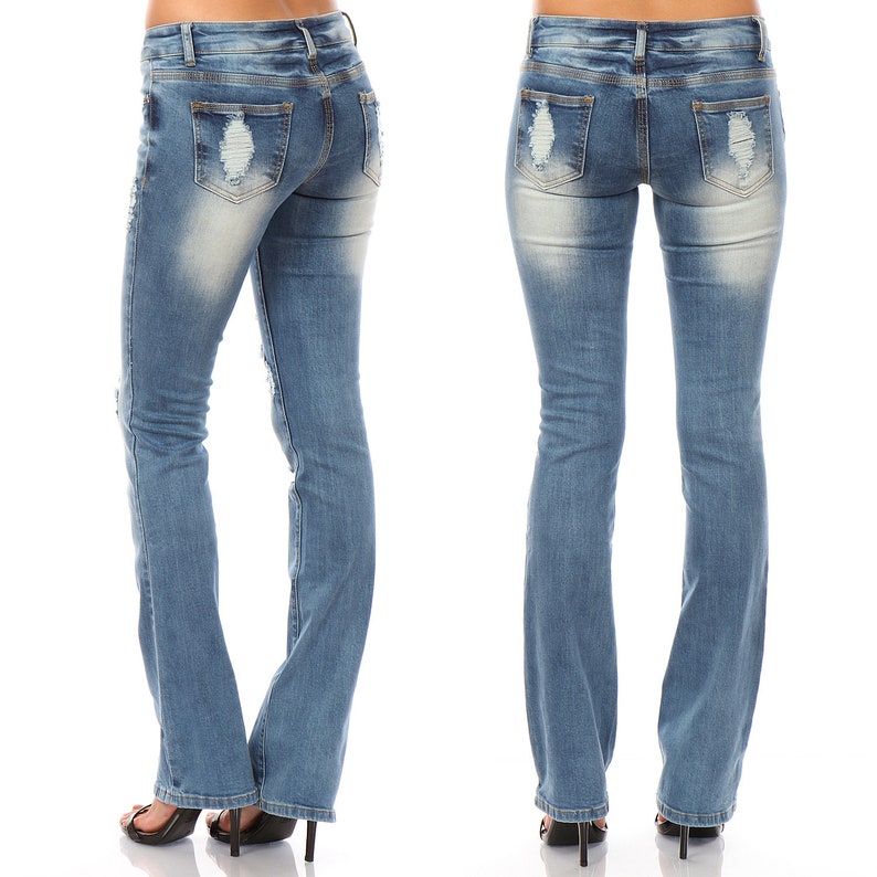 May include: Light blue denim jeans with distressed details on the front and back pockets. The jeans have a slight flare at the bottom and are worn with black high-heeled sandals. The jeans are a classic style.