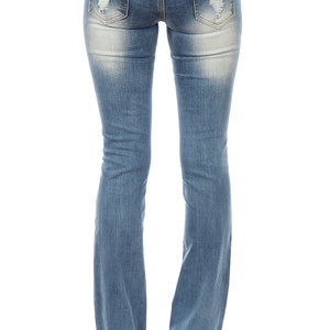 May include: Light blue denim jeans with distressed details on the back pockets. The jeans have a bootcut leg opening and are worn with black high heels. The jeans are faded in areas for a worn look.