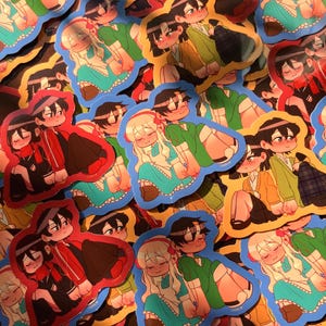 Puede incluir: Una colección de pegatinas coloridas con ilustraciones de parejas al estilo anime. Las pegatinas tienen un borde azul y representan personajes con varios atuendos, incluyendo chaquetas verdes, rojas y amarillas, y vestidos. El tema general es el romance y la amistad.