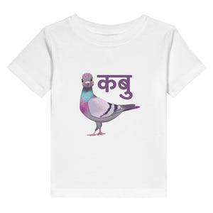 Puede incluir: Camiseta blanca con una colorida ilustración de una paloma. El ave tiene detalles en morado y azul, y la palabra "कबु" está impresa encima en morado. La camiseta está hecha de un material suave y cómodo.