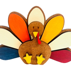 May include: A wooden turkey figurine with a brown body and a colorful tail. The tail feathers are painted in shades of orange, yellow, white, blue, and red.