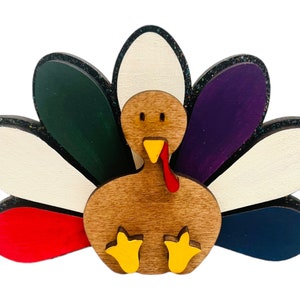 May include: A wooden turkey figurine with a brown body, red wattle, yellow feet, and a colorful tail with white, green, purple, red, and blue feathers.