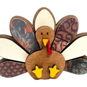 May include: A wooden turkey figurine with a brown body, red wattle, yellow feet, and a patterned tail with white, brown, and blue accents.
