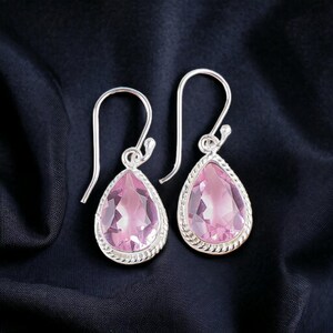 Puede incluir: Un par de pendientes de plata con piedras preciosas de color rosa en forma de lágrima.