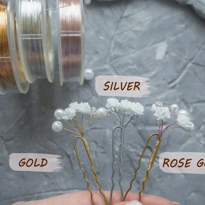 May include: Three hair pins with white flowers and pearl accents. The pins are available in gold, silver, and rose gold.