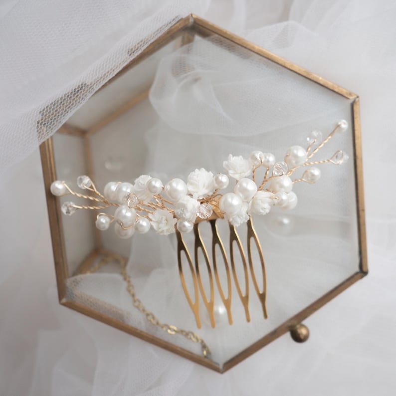 May include: A gold-toned hair comb featuring a decorative arrangement of white faux pearls, small white fabric flowers, and clear crystal beads wired onto thin gold metal branches extending from the top of the five-pronged hair comb base.