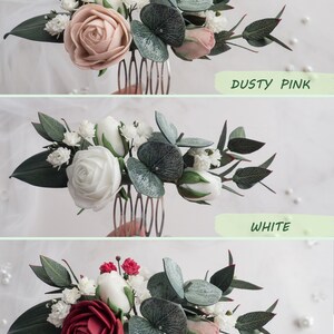 May include: A floral hair comb featuring a dusty pink, white, or burgundy rose, surrounded by green leaves and small white flowers. The comb is made of metal and is designed for bridal or special occasion hairstyles. The text "Dusty Pink", "White", and "Burgundy" are visible.
