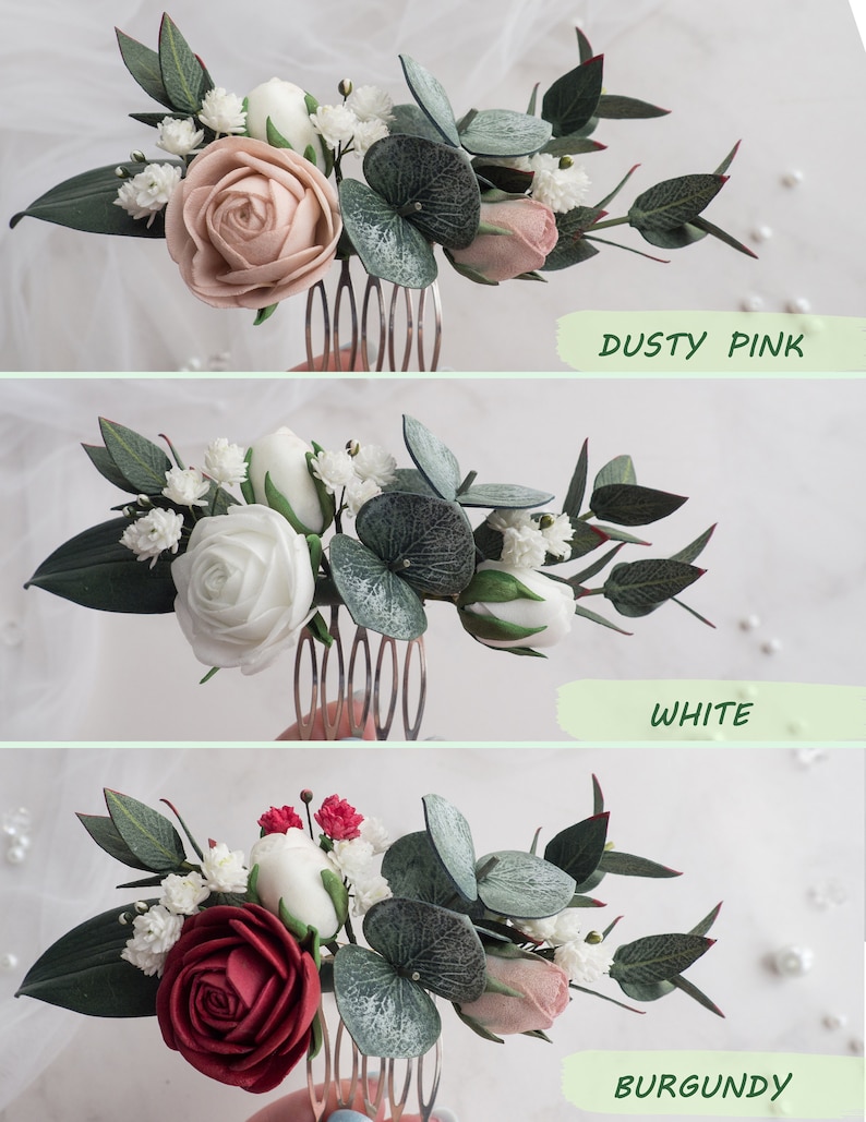 May include: A floral hair comb featuring a dusty pink, white, or burgundy rose, surrounded by green leaves and small white flowers. The comb is made of metal and is designed for bridal or special occasion hairstyles. The text "Dusty Pink", "White", and "Burgundy" are visible.