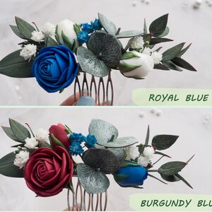 May include: Floral hair comb featuring a royal blue rose, white buds, and small blue flowers, accented with green leaves. The text "ROYAL BLUE" is displayed below the comb. A second comb with a burgundy rose is also shown, with the text "BURGUNDY BLUE".