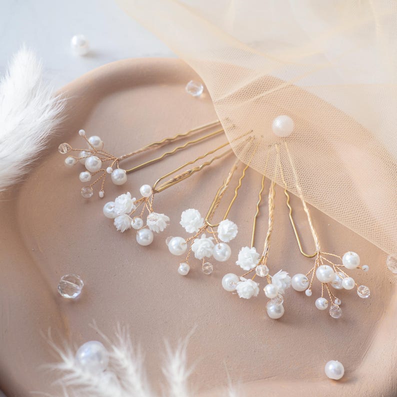 May include: A set of five gold-toned hair pins featuring delicate wire branches adorned with small white faux pearls, clear crystal beads, and tiny white fabric flowers. Each pin has a U-shaped metal base for securing into various hairstyles.