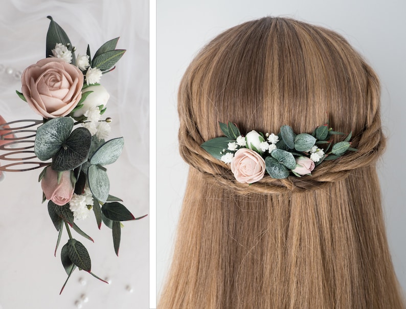 May include: A floral hair comb featuring a large, light pink rose, smaller pink buds, white flowers, and green leaves. The comb is designed with a mix of textures and colors, perfect for bridal or special occasion hairstyles.