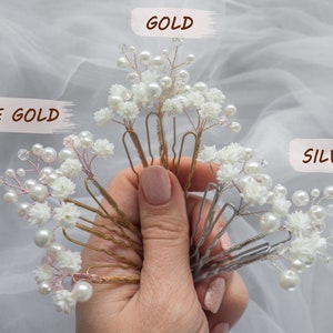 May include: A set of hair clips with white flowers and pearls. The clips are available in gold, rose gold, and silver.