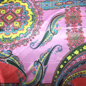 May include: A satin fabric scarf featuring a vibrant, multi-colored paisley and mandala pattern. The design includes shades of pink, yellow, red, turquoise, and black, with intricate floral and teardrop motifs arranged in a repeating, symmetrical layout.