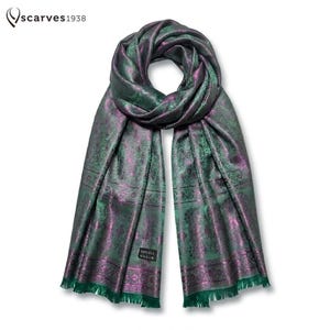 Pode incluir: Um cachecol longo com um padrão paisley em verde profundo e roxo iridescente com textura tecida. O cachecol inclui uma etiqueta preta com a inscrição 100% SILK e tem bordas com franjas. O logótipo scarves1938 é visível no canto superior.