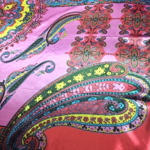 May include: A vibrant silk scarf featuring a complex paisley pattern in shades of hot pink, bright yellow, turquoise, and red. The design includes intricate floral motifs, swirling teardrop shapes, and geometric borders printed on a smooth fabric.