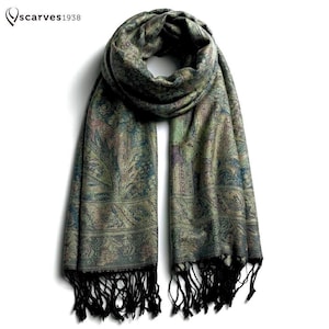 May include: A rectangular scarf featuring an intricate paisley pattern in shades of green, blue, and gold. The scarf has a woven texture and is finished with long black fringe tassels at both ends. The text "scarves1938" appears in the top left corner.