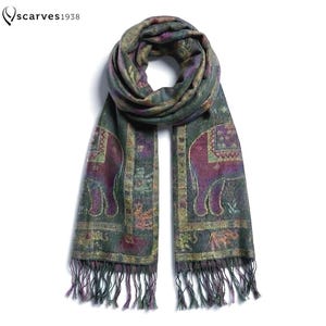 May include: A rectangular scarf featuring a dark green base with purple elephant motifs and intricate gold-toned border patterns. The scarf includes the text "scarves1938" in the top left corner and is finished with long, thin fringe at both ends.
