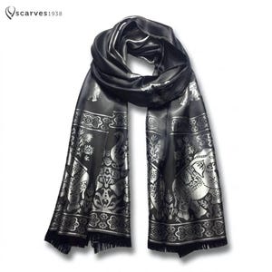 Puede incluir: Una bufanda negra con un patrón de elefantes y flores en color plata metálico con un diseño de borde repetitivo. La bufanda incluye el texto "scarves1938" en la esquina superior izquierda y tiene un dobladillo con flecos en ambos extremos.