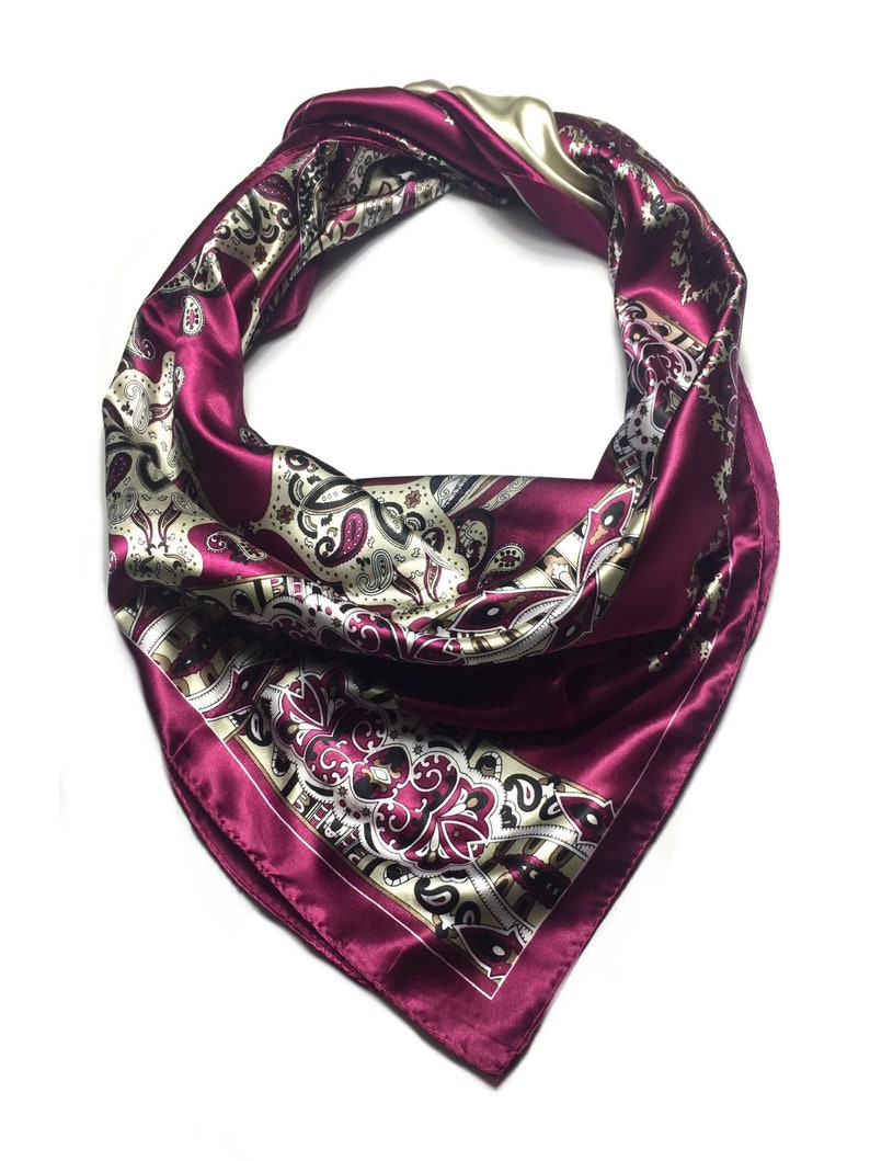 May include: A burgundy satin scarf with a paisley pattern in shades of cream, brown, and black.