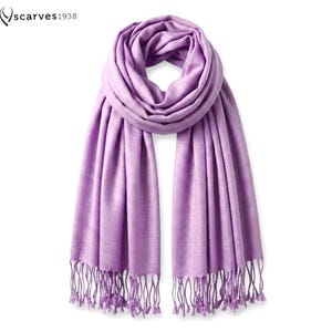 May include: A solid light purple scarf featuring a soft, woven texture and a draped design. The scarf includes long, thin fringe detailing along both bottom edges. The text "scarves1938" is visible in the upper left corner of the image.
