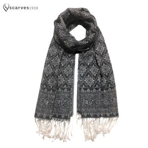 以下が含まれることがあります： フリンジが付いた黒と白のパターンのスカーフ。パターンは繰り返しの花柄です。