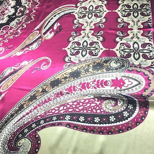 May include: A pink and green paisley patterned fabric with a satin finish. The fabric features a large paisley design in the center, surrounded by smaller paisley motifs.