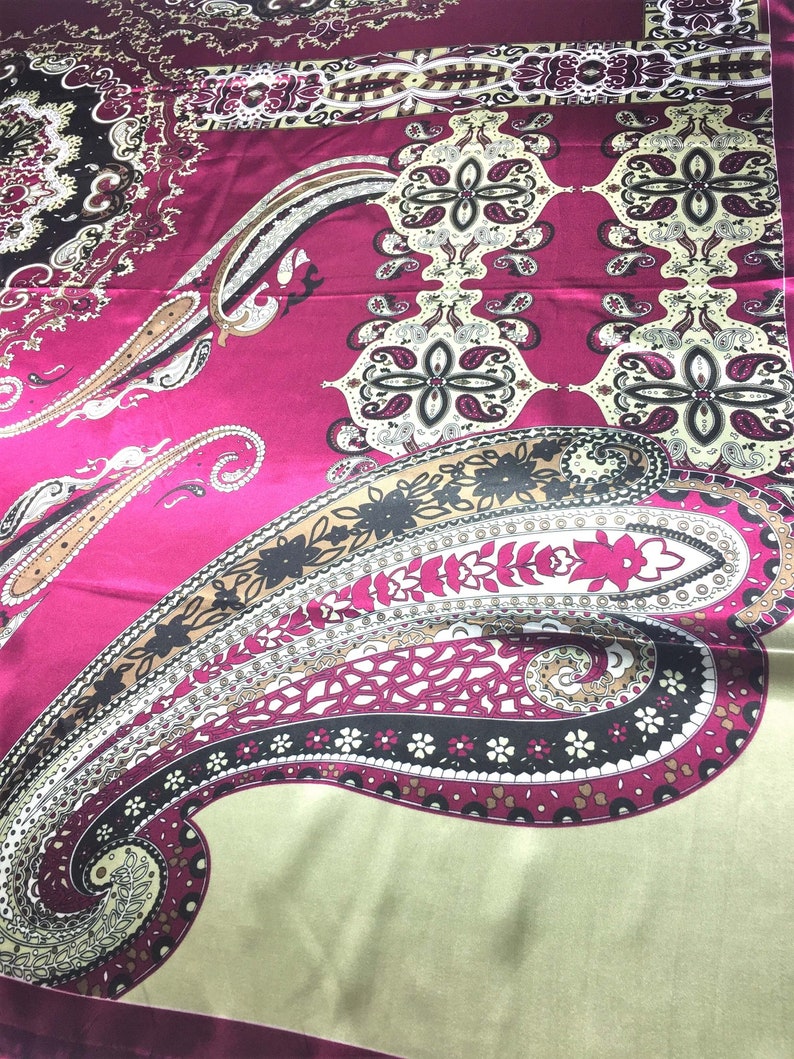 May include: A pink and green paisley patterned fabric with a satin finish. The fabric features a large paisley design in the center, surrounded by smaller paisley motifs.