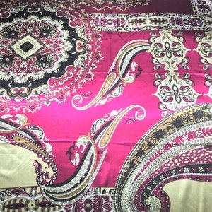 May include: A pink silk scarf with a paisley pattern in shades of brown, black, and cream. The scarf has a decorative border.