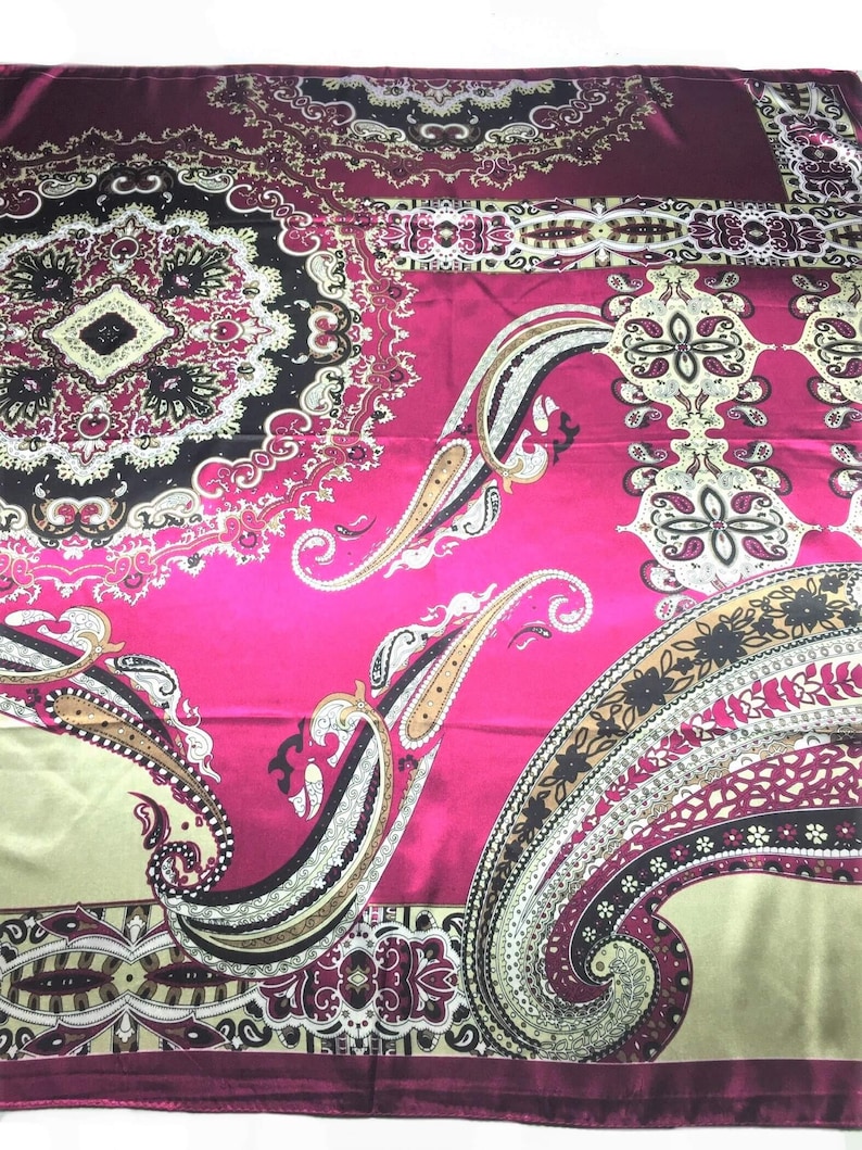 May include: A pink silk scarf with a paisley pattern in shades of brown, black, and cream. The scarf has a decorative border.