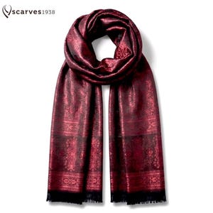 May include: A deep red scarf featuring a dark, intricate woven paisley pattern throughout the fabric. The scarf has a looped neck section and two long, hanging ends with a fringed hem. The text "scarves1938" is visible in the top left corner.