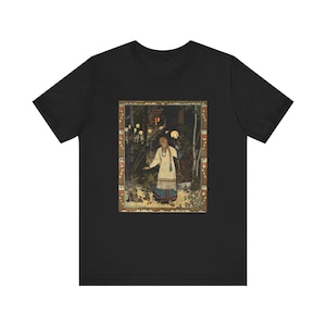 Puede incluir: Camiseta negra con una ilustración enmarcada de una persona con un vestido blanco en un bosque. La ilustración vintage tiene una paleta de colores cálidos, que representa una escena nocturna con orbes brillantes y un edificio al fondo.