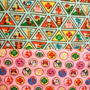 May include: Two fabric patterns. The top pattern features triangular shapes with various cartoon animals and symbols in red, yellow, and green on a light blue background. The bottom pattern is pink with circular designs featuring similar motifs.