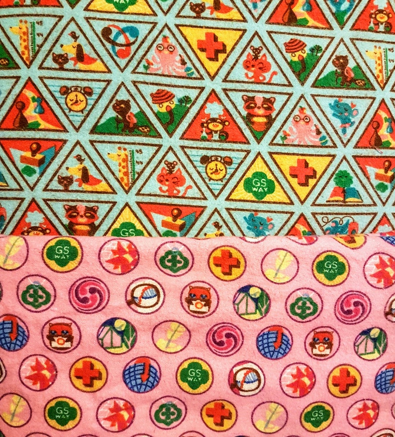 May include: Two fabric patterns. The top pattern features triangular shapes with various cartoon animals and symbols in red, yellow, and green on a light blue background. The bottom pattern is pink with circular designs featuring similar motifs.